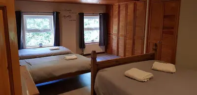 two beds in a room with two windows at Hilltop Cottage/ Penrhiw in Maentwrog