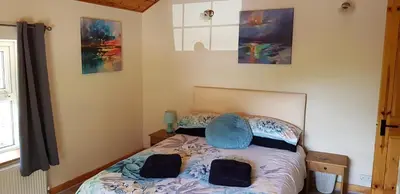 a bedroom with a bed and some paintings on the wall at Hilltop Cottage/ Penrhiw in Maentwrog
