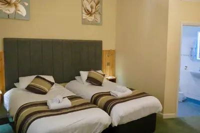 two beds in a hotel room with towels on them at Burton Hotel in Kington