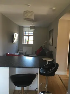 a kitchen and living room with a black counter and stools at Victorian Church Flat 3 in Oswestry