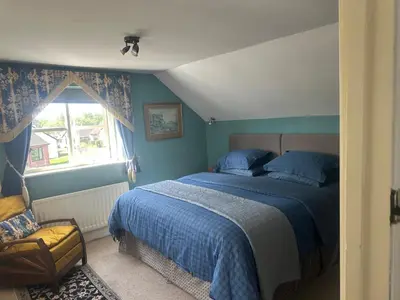 a bedroom with a bed and a chair and a window at Tallow House in Ludlow