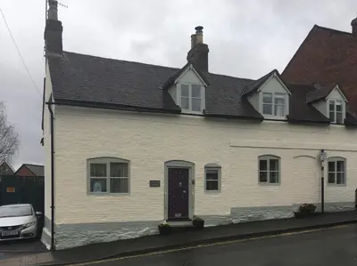 a white house with a car parked in front of it at Tallow House in Ludlow