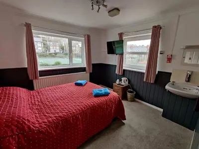 a bedroom with a red bed and a sink at Llwynygog Guest House in Aberystwyth