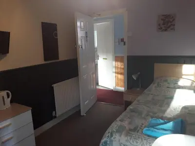 a bedroom with a bed and a door to a doorway at Llwynygog Guest House in Aberystwyth