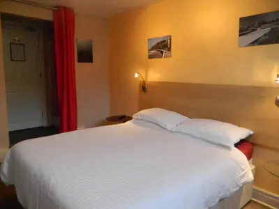 a bedroom with a large white bed with a red curtain at Llwynygog Guest House in Aberystwyth