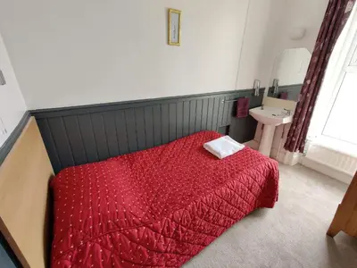 a bedroom with a red bed and a sink at Llwynygog Guest House in Aberystwyth
