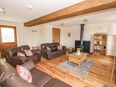 a living room with leather furniture and a fireplace at Pentre Fawr in Llanddewi Ystradenny
