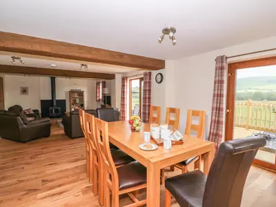 a dining room and living room with a wooden table and chairs at Pentre Fawr in Llanddewi Ystradenny