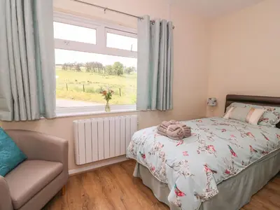 a bedroom with a bed and a window and a chair at Tegfan in Rhayader