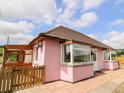 a small pink house with a wooden fence at Tegfan in Rhayader