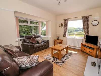 a living room with a leather couch and a television at Tegfan in Rhayader