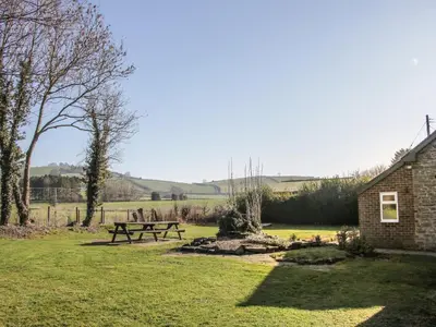 a picnic table in a field next to a building at Bicton Cottage in Acton