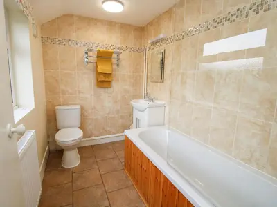 a bathroom with a tub and a toilet and a sink at Bicton Cottage in Acton