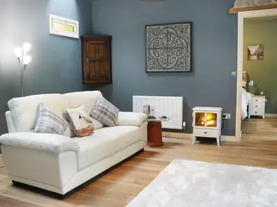 a living room with a white couch and a fire place at Woodpecker Cottage in Ludlow