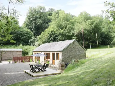 a cottage with a table and chairs in front of it at Woodpecker Cottage in Ludlow
