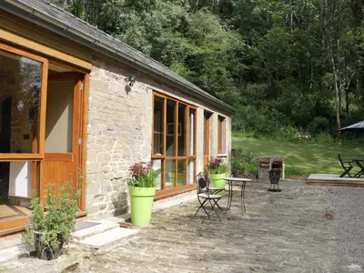 a stone house with a patio and a table and chairs at Woodpecker Cottage in Ludlow