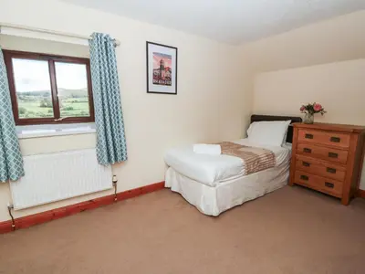 a bedroom with a bed and a dresser and a window at Glanyrafon in Rhayader