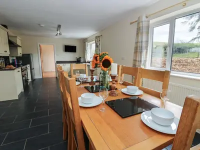 a dining room and kitchen with a wooden table and chairs at Glanyrafon Bungalow in Rhayader