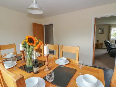 a dining room table with flowers and wine glasses at Glanyrafon Bungalow in Rhayader