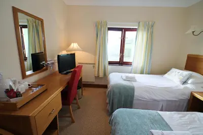a hotel room with two beds and a desk with a mirror at Llety Ceiro Guesthouse in Aberystwyth