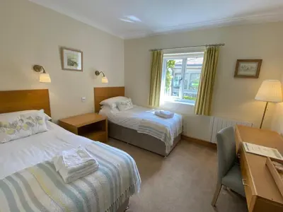 a hotel room with two beds and a desk at Llety Ceiro Guesthouse in Aberystwyth
