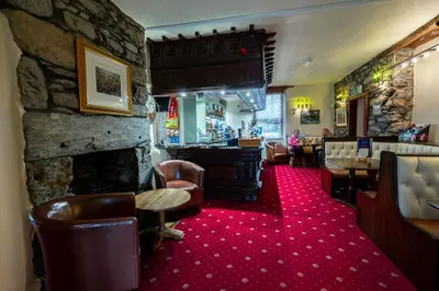 a lobby with a fireplace and a bar with chairs at Grapes Hotel, Bar & Restaurant Snowdonia Nr Zip World in Blaenau-Ffestiniog