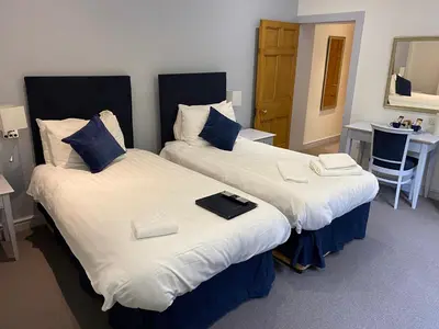 two beds sitting next to each other in a room at Grapes Hotel, Bar & Restaurant Snowdonia Nr Zip World in Blaenau-Ffestiniog
