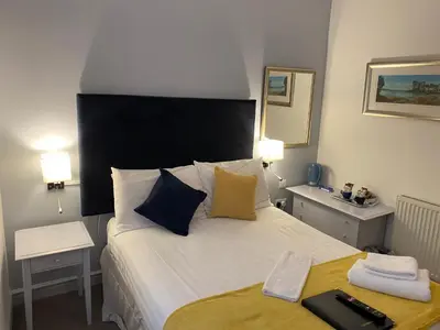 a bedroom with a large bed with a black headboard at Grapes Hotel, Bar & Restaurant Snowdonia Nr Zip World in Blaenau-Ffestiniog