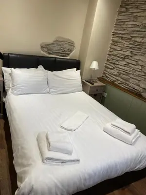 a white bed with two towels on it at Grapes Hotel, Bar & Restaurant Snowdonia Nr Zip World in Blaenau-Ffestiniog
