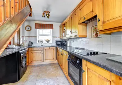 a kitchen with wooden cabinets and a black dishwasher at 1 Bed in Nantygwreiddyn oc-bow49 in Sennybridge
