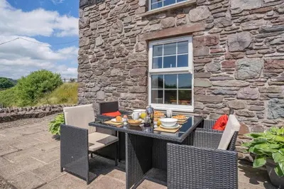 a patio with a table and chairs and a stone building at 1 Bed in Nantygwreiddyn oc-bow49 in Sennybridge