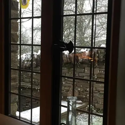 a window with a view of a stone wall at The House In The Hills in Velindre