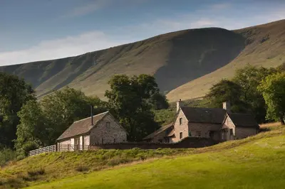 an old house on a hill with a mountain in the background at The House In The Hills in Velindre