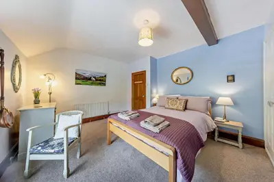 a bedroom with a king sized bed and a chair at 3 Bed in Machynlleth oc-bow43 in Corris