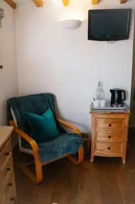 a chair with a green pillow sitting next to a dresser at Henllys Estate B and B in Llandovery