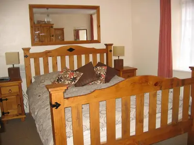 a bedroom with a wooden bed and a mirror at The Horseshoe Guesthouse in Rhayader