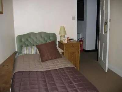 a bedroom with a bed with a green headboard and a table at The Horseshoe Guesthouse in Rhayader