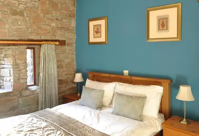 a bedroom with a bed and a stone wall at Black Mountain Lodge in Glasbury