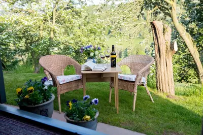 a table with a bottle of wine and two chairs at GoldenValley Shepherd's Hut in Dorstone