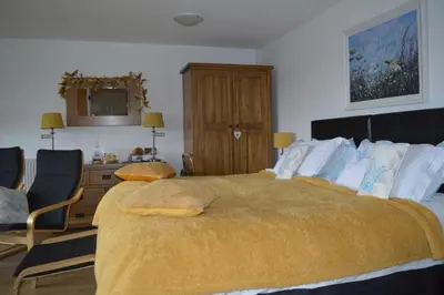 a bedroom with a large bed with a yellow blanket at Smithfield Farm Bed & Breakfast in Builth Wells