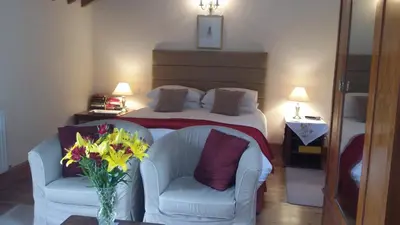 a bedroom with a bed with two chairs and a vase of flowers at The Granary in Talgarth