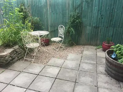 a patio with two chairs and a table and a fence at The Flat Frank Lewis House in Hay-on-Wye