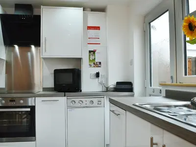 a kitchen with white cabinets and a microwave at Lle Clyd in Harlech