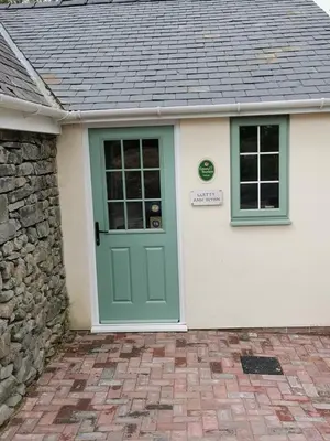 a house with a green door and a stone wall at Lletty Ann wynn at Fraithwen Cottages in Newtown