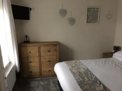 a bedroom with a bed and a dresser and a television at Swyn y Mor beach close Pet friendly hot tub in Barmouth