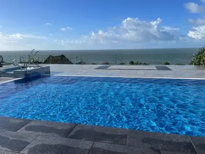 a large blue swimming pool with the ocean in the background at Swyn y Mor beach close Pet friendly hot tub in Barmouth