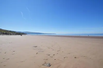 a beach with footprints in the sand and the ocean at 2 Bed in Barmouth oc-bow52 in Llanaber