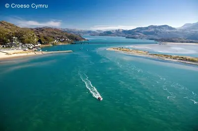 a boat in the water next to a beach at 2 Bed in Barmouth oc-bow52 in Llanaber