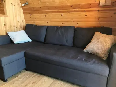 a gray couch in a room with wooden walls at Cil y Coed Luxury Pod in Machynlleth