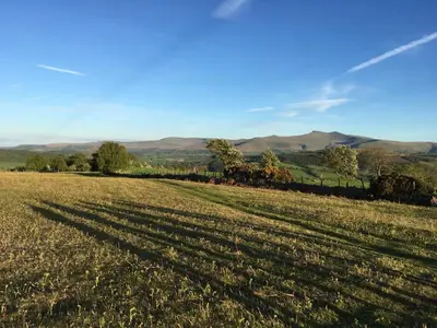 a long shadow of a field with mountains in the background at Ty Glo Cottage in Brecon